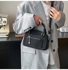 Détail d'un sac bowling noir avec pendentif cœur et bandoulière réglable