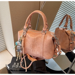 Detailed view of pink orange Boston bag with embossed letters and cute bear charm