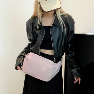 Gros plan du sac bandoulière en nylon rose avec texture froissée sur veste en cuir noir