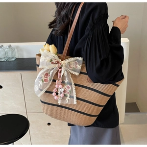 Detail der Strohtasche mit Spitzenschleife, Blumenstickerei und Perlenanhänger