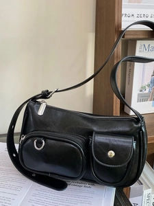 Minimalist black PU leather shoulder bag with silver hardware on a wooden shelf