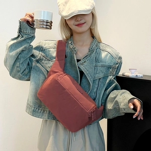 Modèle portant un sac de poitrine en nylon rouge brique avec bandoulière et double zip