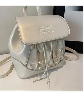 Close-up of metallic pearlescent mini backpack featuring pearl charms and logo embossing