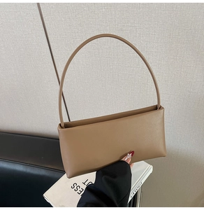 Close-up of minimalist brown leather shoulder bag with smooth matte finish in a lifestyle setting