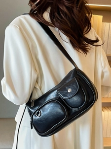 Glossy black leather shoulder bag with dual front pockets shown on female model