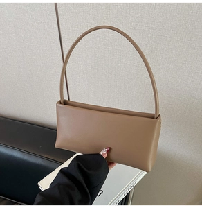 Close-up of minimalist brown leather shoulder bag with unique arched handle design