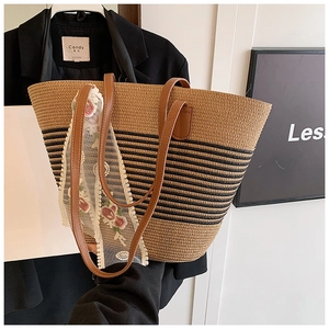 Detail of striped woven straw tote with leather handles and embroidered floral lace ribbon