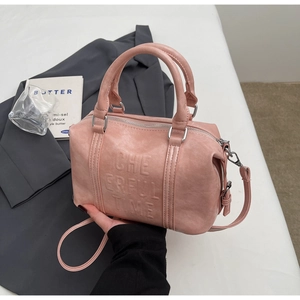 Detail of pink Boston bag with embossed lettering on textured synthetic leather