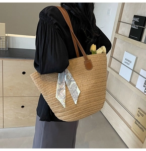 Large straw tote bag detail with leather handles and decorative floral silk scarf