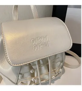 Close-up of mini cream backpack with pearl accents and embossed ARM logo detail