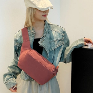 Détail du sac de poitrine en nylon rouge brique avec bandoulière large et fermeture