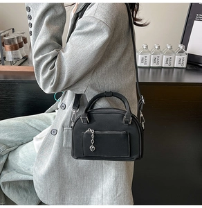 Dettaglio della borsa bowling nera con texture opaca e ciondolo a cuore indossata