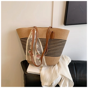 Detail of straw tote bag with black stripes, floral lace ribbon and brown PU straps