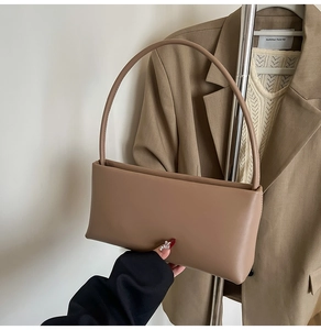 Detail shot of a minimalist brown leather underarm bag with sleek stitching and clean lines