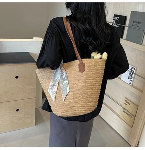 Detail of hand-woven straw tote with brown leather strap and colorful silk scarf detail