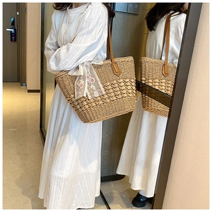 Detail of hand-woven straw tote bag with lace bow and embroidered floral accents