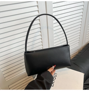 Detail of minimalist black matte PU leather underarm bag with slim shoulder strap