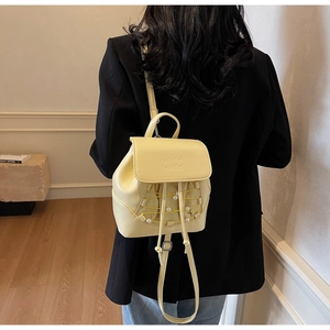 Close-up of yellow leather mini backpack with pearl accents and drawstring detail