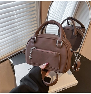 Dettaglio di una borsa Boston marrone opaca con catena a cuore e riflesso nello specchio