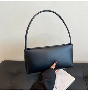Detailed view of the smooth black leather texture and sleek curved strap of the shoulder bag