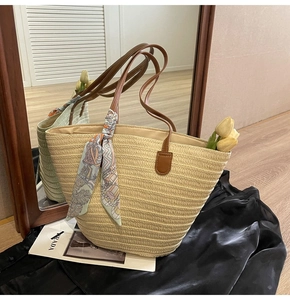 Detail of hand-woven straw tote with leather straps and decorative vintage silk scarf
