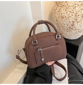 Vista dettagliata della borsa bowling marrone con ciondolo a cuore e texture opaca