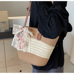 Detail der Strohtasche mit weißer Spitze und großer Blumenschleife mit Perlenbesatz