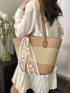 Large straw tote bag with brown leather straps and floral lace scarf for beach