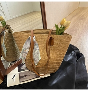 Detail of straw tote bag with brown leather handles and a colorful floral silk scarf