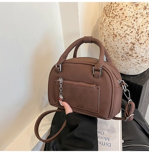 Dettaglio borsa a bauletto marrone opaco con catena a cuore e finiture argentate