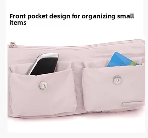 Detailed view of light pink nylon bag featuring front pockets and metal snap buttons
