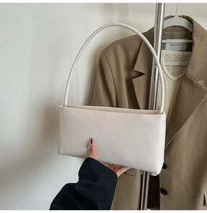 Detail of minimalist cream leather shoulder bag with sleek strap and premium texture