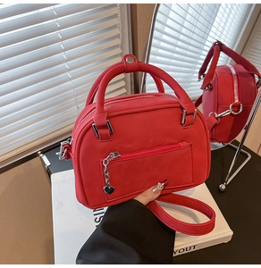 Dettaglio della borsa bowling rossa con texture opaca e ciondolo a cuore argentato
