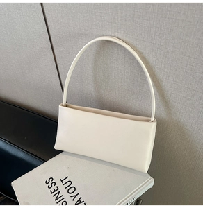 Minimalist cream white leather baguette bag displayed on a business layout book