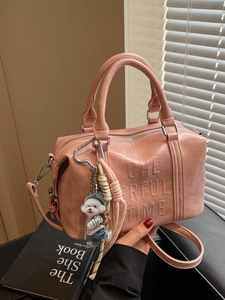 Pink Boston handbag with embossed letters and cute dog charm shown in hand