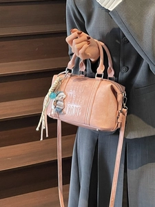 Pink leather Boston handbag with embossed letters and cute dog charm shown with grey suit
