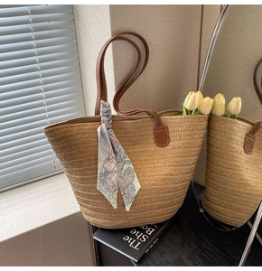 Detail of straw tote bag with brown leather handles, floral scarf, and tulip inside
