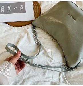 Detail of olive green leather bag with silver LOUIESAMAN metallic logo and chain strap