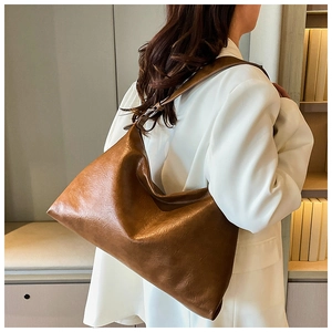 Brown soft leather tote bag showing drape and texture in a professional lifestyle setting