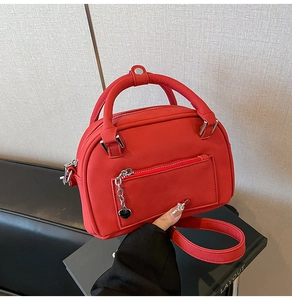 Dettaglio borsa bowling rossa con ciondolo a cuore, catena in metallo e finitura opaca