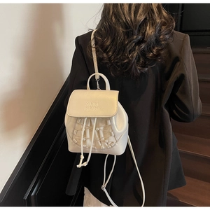 Detail of white mini backpack featuring pearl grid decor and embossed texture