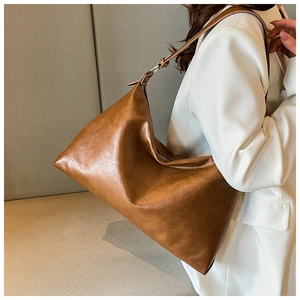 Detailed texture of a brown vintage tote bag worn over a white suit blazer