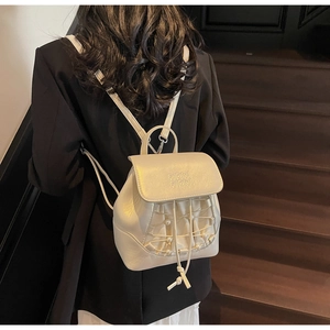 Detail of mini cream backpack with quilted pearl texture on a model in black suit