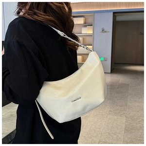 Detail of cream leather shoulder bag with chic silver chain strap and metal logo
