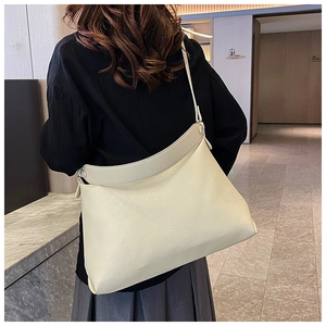 Macro shot of minimalist cream-white textured leather tote bag showing wide shoulder strap
