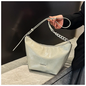 Detail of light green hobo bag with silver chain strap and polished faux leather finish