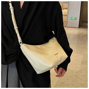 Macro detail of creamy white half-moon crossbody bag with smooth leather and silver logo