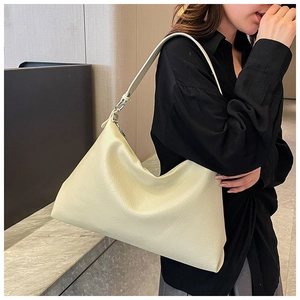 Detail of soft cream-colored hobo bag with textured faux leather and silver metal ring