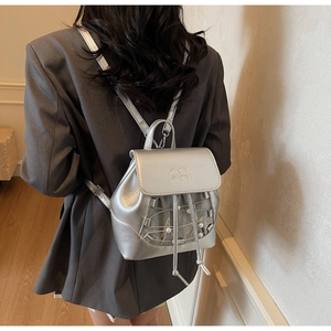 Detail of silver metallic backpack featuring cross drawstring and white pearl accents