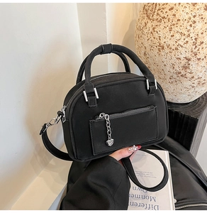 Dettaglio della borsa a bauletto nera opaca con ciondolo a cuore e zip esterna